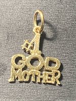 Front view of the gold Godmother pendant charm with 'GOD MOTHER' lettering and number 1 with a cross detail.
