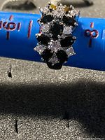 Top view of the ring showing the flower design made with black and clear stones on a silver band.