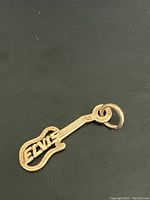 Close-up image of a guitar-shaped pendant with 'ELVIS' integrated into the body in gold color.