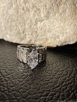 Front view of large sterling silver dinner ring with marquise cut clear stone and channel set smaller stones, size 6.