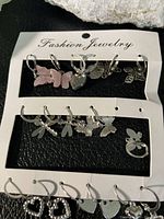 Photo of 9 silver-tone earrings for pierced ears with butterfly, dragonfly, and heart designs on a labeled card 'Fashion Jewelry'. Includes 7 pairs and 2 singles.