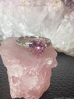 Front view of 925 sterling silver ring with a pink heart-shaped gemstone on a pink crystal background.