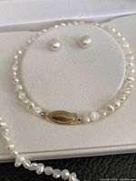 Photo of pearl bracelet and stud earrings in a white jewelry box showing the clasp and pearl details.