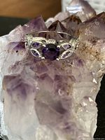 Close-up view of the silver ring with a round purple mystic topaz, displayed on a purple crystal cluster.