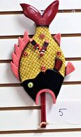 Full view of yellow fish-shaped pendulum wall clock showing red fins and black fish head with clock face and pendulum.