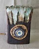 Front view of the slab pottery vase showing textured brown body and circular decorative motif with blue and cream accents.