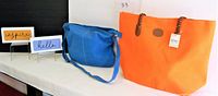Photo showing blue and orange tote bags alongside two inspirational plaques.