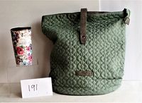 Photo showing large mint-green quilted backpack next to tall floral travel mug with note card labeled 191.