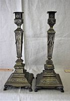 Full view of the pair of antique brass candlesticks side by side showing ornate square bases and detailed design on stems.