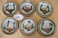 Photo showing six round vintage rustic Mexican ceramic plates arranged in two rows of three on a tan cloth, each plate about 8.75 inches in diameter, with hand-painted rural scenes including animals, plants, and trees in earthy colors.