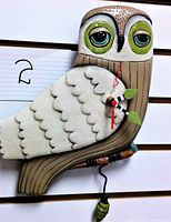 Front view of snow owl clock showing owl details and clock face with hands.