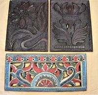 Three carved wooden panels laid out: two unpainted dark wood floral panels on top, and one rectangular colorful carved floral panel below.