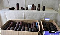 Two large boxes filled with vintage wooden fishing net floats and float pieces, arranged on a surface with some floats standing above the boxes.