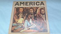 Front cover of vinyl LP sleeve showing America band members framed with native American imagery.
