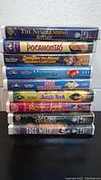 Stack of 11 assorted VHS movie tapes including The Neverending Story, Pocahontas, DuckTales The Movie, The Little Mermaid, 101 Dalmatians, The Jungle Book, The Return of Jafar, The Secret Garden, and Free Willy.