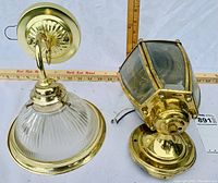 Top down view of two chrome-like wall hanging lanterns; hexagonal lantern and half-moon shaped lantern side by side with measurement ruler for scale.