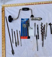 Photo shows the FULLER hand crank drill alongside an assortment of 11 wood spade bits, 3 other drill bits, and 3 new Mastercraft flat wood drill bits in packaging.