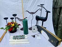 Photo of the lot showing various candle holders, candles and candle snuffers arranged on a white cloth with a wooden ruler for scale.