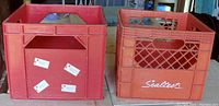 Photo of two stacked plastic milk crates, orange Sealtest branded crate on top and solid red crate below