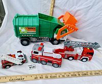 All four toy trucks in set: large green Tonka garbage truck and three red fire trucks