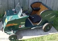 Left side view of vintage customized go kart showing decals, steering, horn, and woven interior