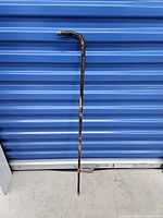 Full view of vintage wooden cane with curved handle and silver capped bottom.