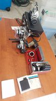 Full view of all cameras, accessories including Canon Super 8 camera, Olympus Trip 35 camera, Bell and Howell flash, Belloscope, lenses, cases and documents on wood table.