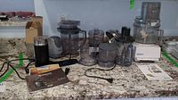 Photo of all items displayed on countertop including food processor, Nespresso machine, chopper, Ninja appliance, assorted containers and manuals.
