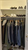 Closet with men's jackets and shoes on shelves above and outerwear hanging on rod