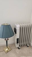 Lamp and heater side by side against white wall, showing full items and power cords.
