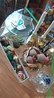 Full view of various glass and plastic ornaments on a table with candlesticks and a glass bowl with pears