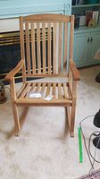 Front view of wooden rocking chair with vertical slats, showing armrests and rocking base