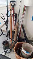 Full view of lot items showing lattice baskets, shepherd hooks, pots, yard sticks, and tools leaning against a wall