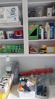 Photo showing shelves with various cleaning supplies including Swiffer mop refills, Lysol cleaner, boxes of light bulbs, and some glass jars and vases.