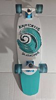 Top view of the complete Kryptonics skateboard, displaying deck with wave graphic, blue trucks and wheels.