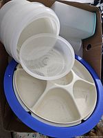 Top view of the divided serving tray with blue rim, white section dividers, and a translucent round strainer insert on top.
