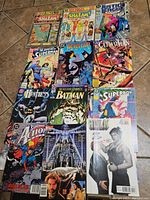 Comic books laid out on the floor, showing front covers of various vintage comics including Shazam!, Justice League, Detective Comics, Catwoman, Superman, Batman, Superboy, and more.