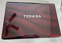 Closed view of glossy dark red Toshiba laptop lid with visible reflections.
