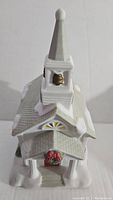 Front view of vintage ceramic church candle holder showing white building, steeple with bell, and wreath on front door.