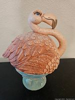 Side profile of flamingo candy dish showing detailed feathers and curved neck, blue base visible.