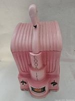 Front view of the pink flamingo cookie jar showing the flamingo's head and neck lid handle with the word 'COOKIES' vertically painted.