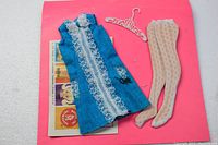 Full lot with dress, stockings, hanger and promotional brochure attached to pink cardboard