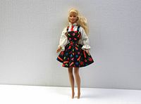 Front view of 1966 Back To School Barbie doll in white blouse, black jumper with colorful number print, and red tie.