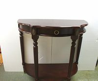 Front view of dark wood half-moon entranceway table showing shape, drawer, legs, and lower shelf.