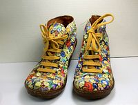 Front view showing lace-up button patterned shoes with yellow laces and rounded toes.