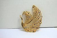 Front view of gold toned swan-shaped brooch adorned with multicolored rhinestones on wings.