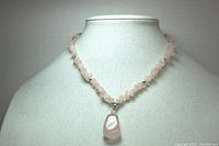 Front view of the rose quartz necklace on a display bust showing the rose quartz chips, silver bead accents, and the large 3 inch rose quartz pendant.