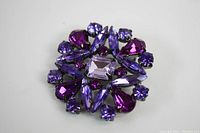 Close-up of the brooch showing detailed arrangement of purple and pink rhinestones in a floral pattern.