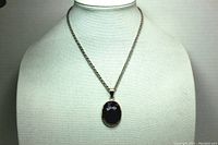 Full view of silver toned chain with purple amethyst pendant on display stand to show full length and style.