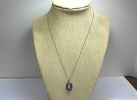 Full view of the pendant on the display bust showing overall size and chain length.